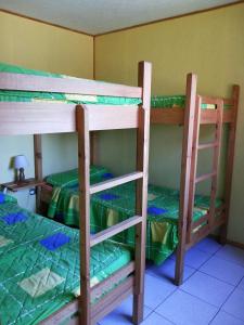 a room with three bunk beds with green sheets at Las Delicias in Maitencillo