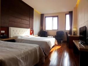 Qingdao Hua Qi Kaiserdom Hotel في تشينغداو: غرفة فندقية بسريرين وتلفزيون بشاشة مسطحة