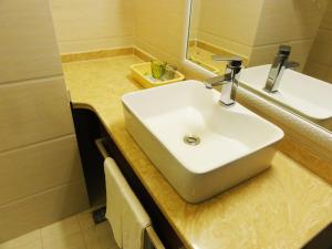 a bathroom with a white sink and a mirror at Qingdao Hua Qi Kaiserdom Hotel in Qingdao