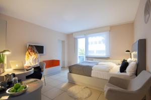 Eine Frau sitzt auf einem Stuhl in einem Schlafzimmer mit einem Bett. in der Unterkunft The Grey Design Hotel in Dortmund