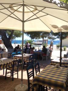 a group of people sitting at tables under an umbrella at Marina in Nikiti