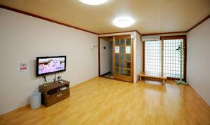 sala de estar con TV de pantalla plana y suelo de madera. en Hwagae Pension, en Hadong