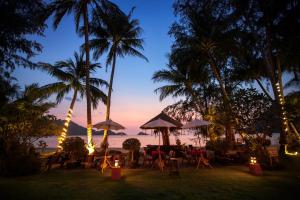 un ristorante sulla spiaggia con palme la sera di Little Sunshine Boutique Beach Resort & Spa a Ko Chang