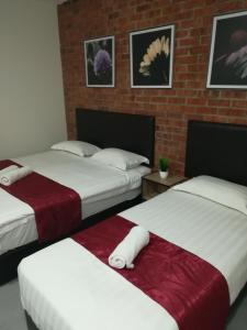 a room with two beds and a brick wall at Rock & Roll Hotel Klang in Klang