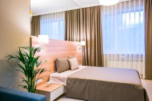 una habitación de hotel con una cama y una planta en Eco Apart Hotel Astana en Astaná