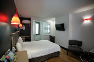 ein Schlafzimmer mit einem weißen Bett und einem Stuhl in der Unterkunft Hôtel Henri IV in Nérac
