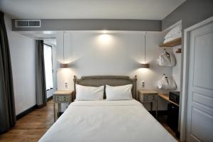 1 Schlafzimmer mit einem Bett mit weißer Bettwäsche und 2 Tischen in der Unterkunft Hôtel Henri IV in Nérac