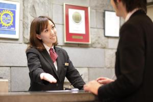 a woman in a suit sitting at a table talking at Hotel Park Side Hiroshima Peace Park in Hiroshima