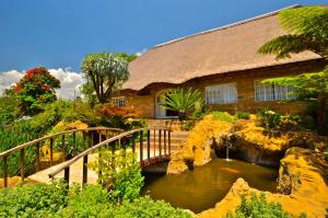 a bridge over a pond in front of a house at Hlalanathi Drakensberg Resort in Bergville