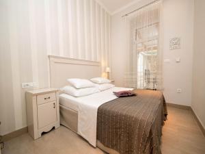 a white bedroom with a bed and a window at Apartments LATINO in Crikvenica