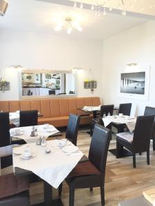 una sala da pranzo con tavoli e sedie bianchi di Lexow - Hotel an de Havenkant a Tönning