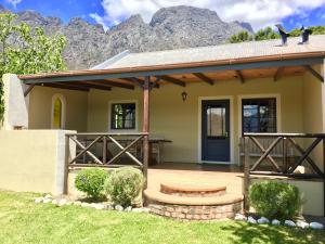 a house with a front porch with mountains in the background at Franschhoek Country Cottages in Franschhoek