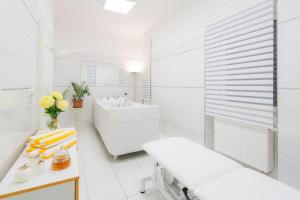 a white bathroom with a tub and a sink at Hotel Palatin in Karlovy Vary