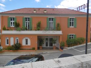 a orange house with green windows and a car parked in front at Hôtel La Flore in Villefranche-sur-Mer