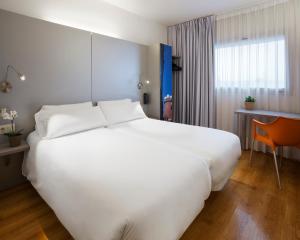 een groot wit bed in een hotelkamer bij B&B HOTEL Figueres in Figueres