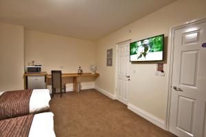 a living room with a television and a couch at New County Hotel by RoomsBooked in Gloucester