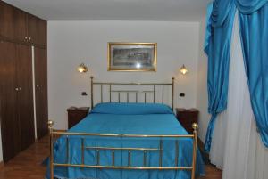 a bedroom with a bed with blue sheets and blue curtains at Arzuni B&B in Civitella Roveto