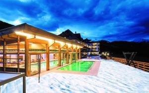 a villa with a swimming pool in the snow at Natur & Aktiv Hotel Rogen in Mühlbach
