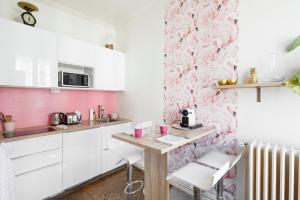 une cuisine avec des placards blancs et du papier peint rose dans l'établissement Ty Paradis by Cocoonr, à Rennes