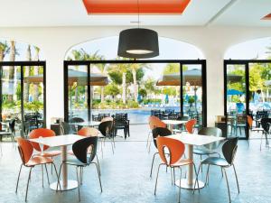 een restaurant met tafels, stoelen en ramen bij Inturotel Sa Marina in Cala d´Or