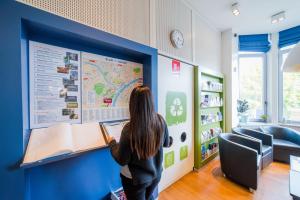 a woman is looking at a map on a wall at Auberge de Jeunesse de Namur in Namur