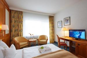 a hotel room with a bed and a flat screen tv at Göbels Landhotel in Willingen