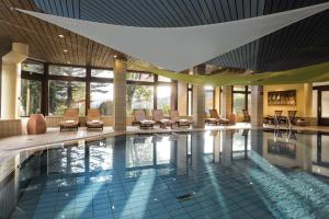 uma piscina num hotel com cadeiras e mesas em Maritim Titisee Hotel em Titisee-Neustadt