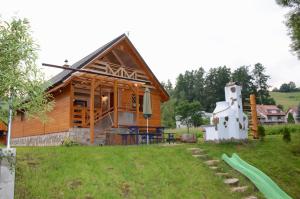 a log cabin with a playground and a statue at Chata Emka in Vyšný Kubín
