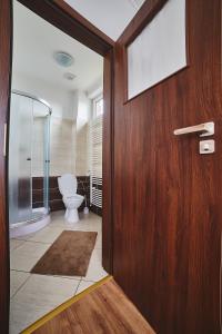 a bathroom with a toilet and a wooden door at Penzión Music in Nižný Slavkov