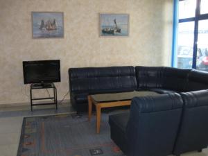 a living room with a black leather couch and a tv at Hotel Astoria in Burgas
