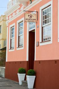 a pink building with two white pots in front of it at Pousada Solar da Lapa in Lapa