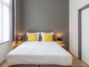 a bedroom with a large white bed with yellow pillows at Urban Suites Brussels Schuman in Brussels