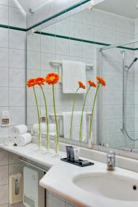 a bathroom with orange flowers in vases on a sink at Hapimag Apartments Athens in Athens