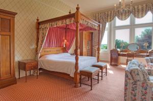 a bedroom with a canopy bed in a room at Tillmouth Park Country House Hotel in Duddo