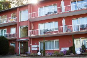 - un immeuble rouge avec des balcons blancs dans l'établissement Appartementhaus Martin, à Badenweiler