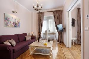 a living room with a purple couch and a table at V1935 Luxurious Apartments in Athens