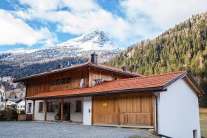 ein Gebäude mit einem schneebedeckten Berg im Hintergrund in der Unterkunft Bauernhof Fuhrmannslochhof in Nauders