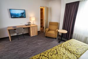 a hotel room with a desk and a bed and a chair at Amrâth Hotel Lapershoek Arenapark in Hilversum
