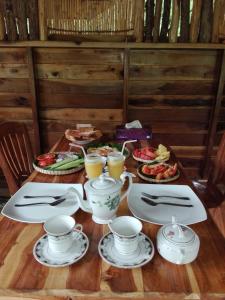 a table with cups and plates of food and drinks at Mount Wood Star in Ella