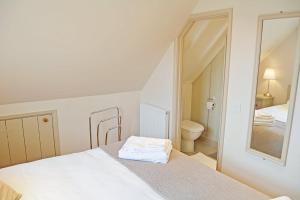 a white bedroom with a bed and a mirror at Weavers Loft in Erpingham