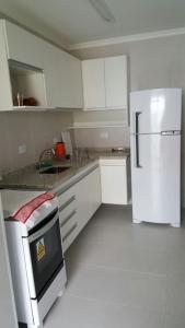 a kitchen with white cabinets and a white refrigerator at Apartamento Aconchegante in Ubatuba