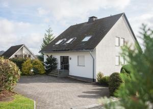 ein weißes Haus mit einem schwarzen Dach und einer Auffahrt in der Unterkunft Ferienwohnung Traumblick in Winterberg