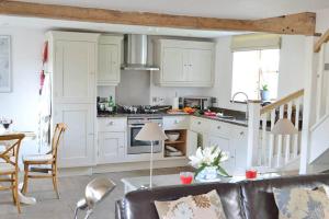 una cocina con armarios blancos y una mesa en una habitación en Hampton Wafre Cottage, en Docklow