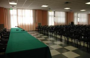 una sala conferenze con tavolo e sedie verdi di Hotel Cavallino a Faenza