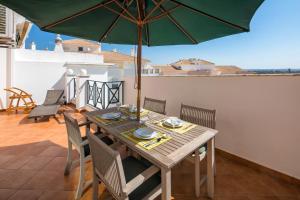 una mesa de madera con sillas y una sombrilla en el balcón en Penthouse Casa Torre en Armação de Pêra