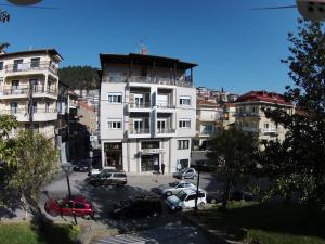 a large white building with cars parked in a parking lot at Hotel Orestion - Bike and motorcycle friendly hotel in Kastoria