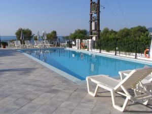 a swimming pool with two lounge chairs next to it at Andreolas Beach Hotel in Laganas