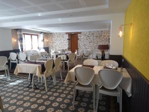 uma sala de jantar com mesas e cadeiras brancas em L'auberge Des 3 Ponts em Cusance