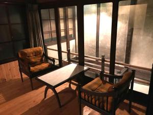 ein Wohnzimmer mit einem Tisch, Stühlen und einem Fenster in der Unterkunft YUMEJI Vintage Villa in Kyoto