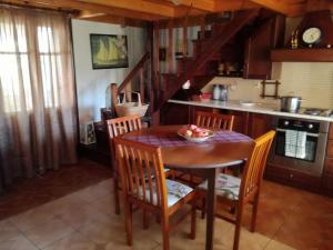 a kitchen with a wooden table and chairs and a kitchen with a staircase at Roula House in Nýmfai